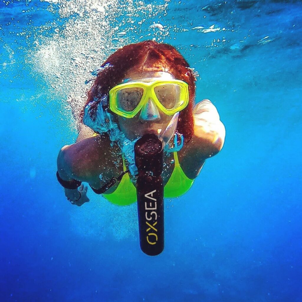 Una mujer practicando snorkel utilizando la botella de aire OX500